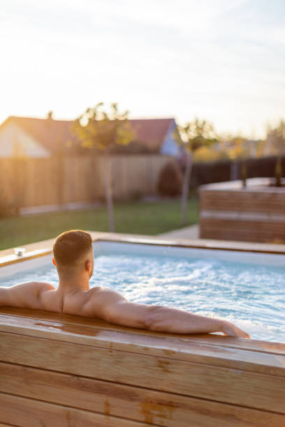Mid - adult man having a relaxing time in an outdoor hot tub in the countryside. He looks relaxed and calm.