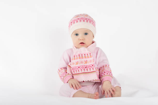 Adorable baby in white sunny bedroom. Toddler girl on white background. Nursery for young children. Textile and bedding for kids. Family morning at home. New born kid.