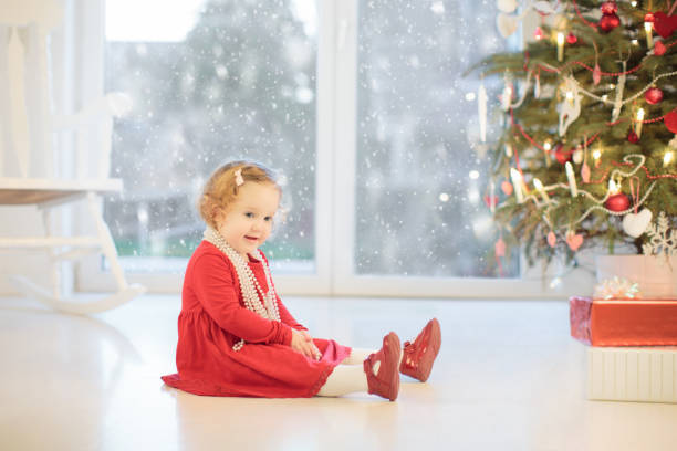 Child decorating Christmas tree at home. Little boy and girl in pajamas with Xmas ornament. Family with kids celebrate winter holidays. Kids decorate living room and fireplace for Christmas.