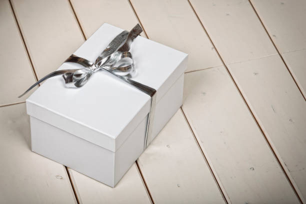 istock White gift box with silver ribbon bow on wooden planks 2181577989