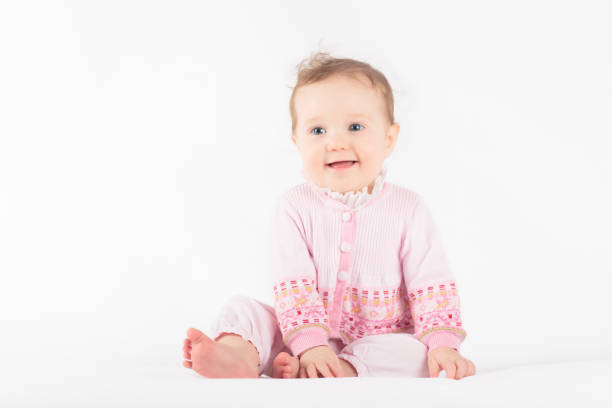 Adorable baby in white sunny bedroom. Toddler girl on white background. Nursery for young children. Textile and bedding for kids. Family morning at home. New born kid.