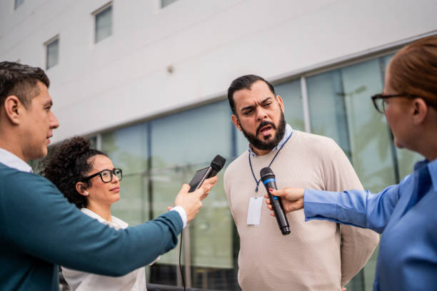 Mature man talking to journalists outdoors