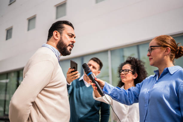 Mature man talking to journalists outdoors