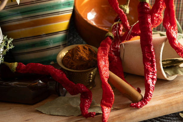 A vibrant and colorful arrangement of dried red peppers and a variety of spices placed on a rustic wooden surface
