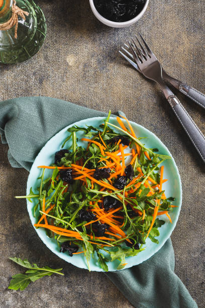 Vegetarian salad with prunes, herbs and carrots on a plate top and vertical view