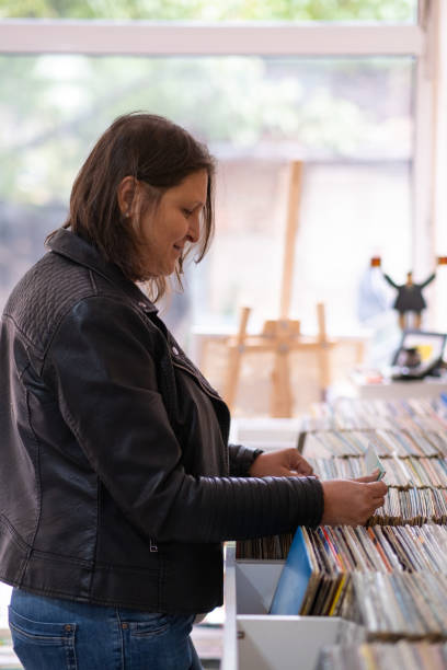 istock Record shops. A woman in a black leather jacket in a record store. 2181587589