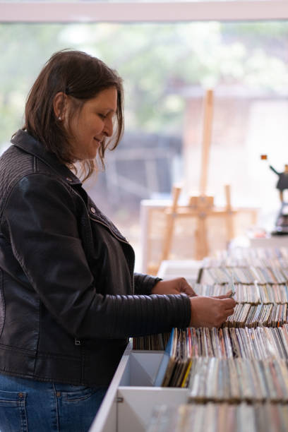 istock Record shops. A woman in a black leather jacket in a record store. 2181587590