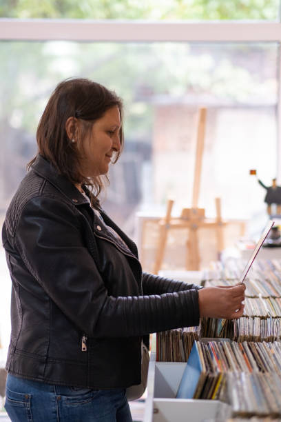 istock Record shops. A woman in a black leather jacket in a record store. 2181587596