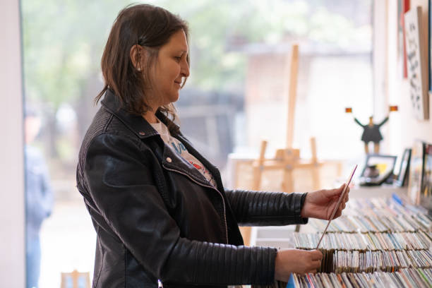 istock Record shops. A woman in a black leather jacket in a record store. 2181587612