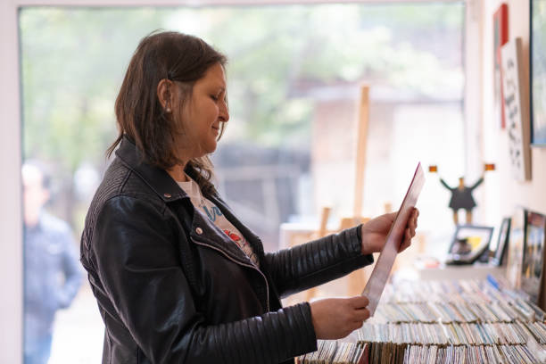 istock Record shops. A woman in a black leather jacket in a record store. 2181587641