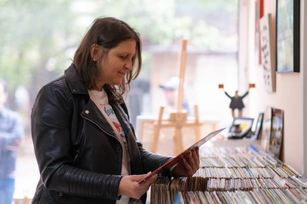 istock Record shops. A woman in a black leather jacket in a record store. 2181587644