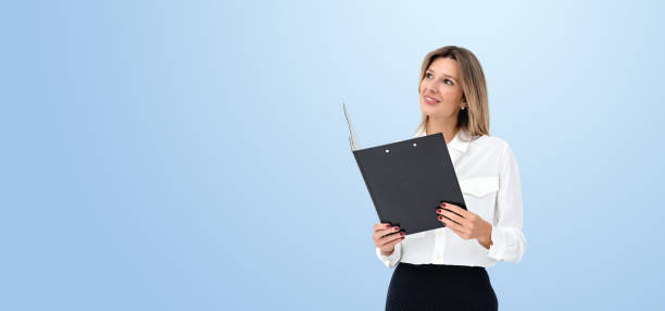 istock Woman in white shirt holding black folder on blue background. 2181592566