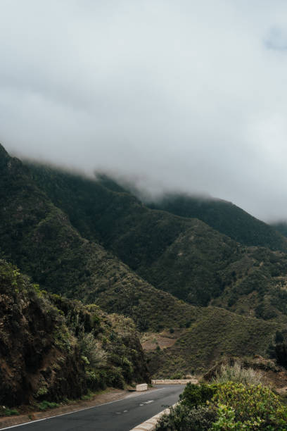 istock Serene winding road through lush green mountains under cloudy skies 2181592740