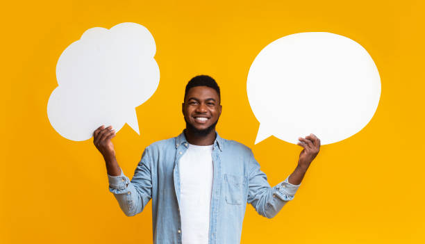istock African american man holding two speech bubbles on yellow background 2181604426