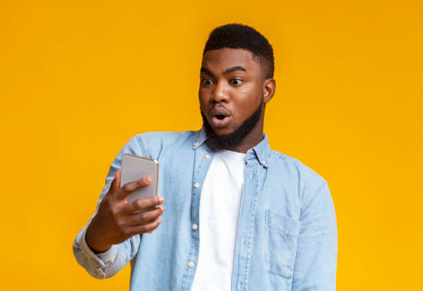 istock Surprised african man looking at smartphone screen with mouth opened 2181604499