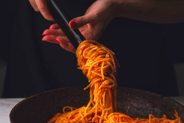 istock Spaghetti all'assassina is a typical Apulian recipe, Bari. Trendy first course, pasta cooked directly in a pan with tomato sauce, crunchy and spicy flavor. Chef's woman hands serving pasta 2181609647