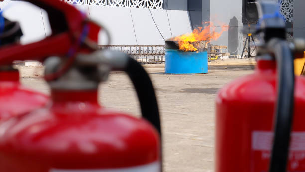 istock Two blurred red fire extinguishers in the foreground, focused on a burning barrel in a construction zone. 2181615512