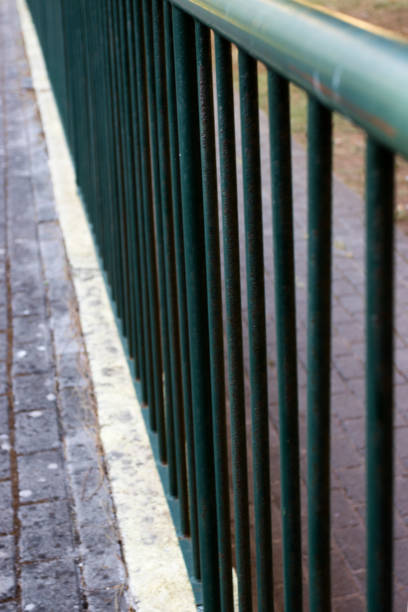Green painted railing on a street.