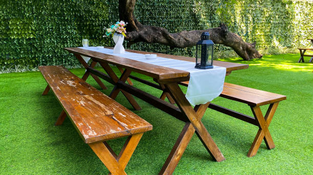istock Wooden picnic table and bench set with white table runner on green grass 2181618407