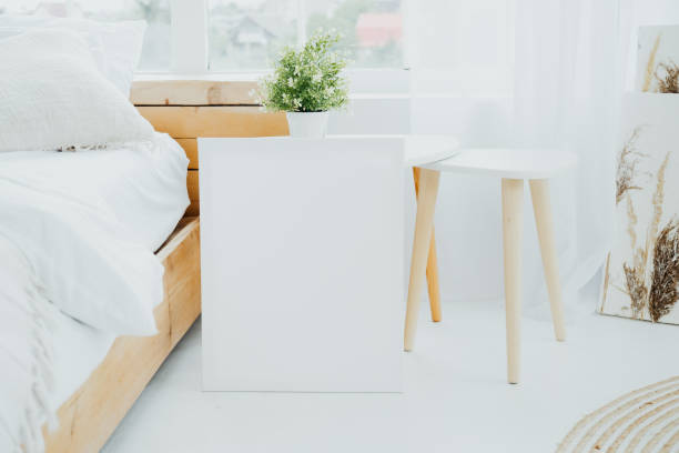 istock Bright and minimalistic bedroom featuring a white nightstand, potted plant, and light decor 2181622177
