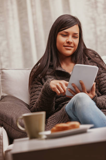 istock Young woman using tablet and relaxing on sofa at home 2181645734