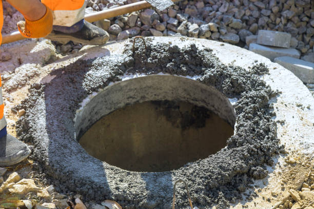 istock Manhole for utility pit is being formed by placing concrete along its top a border. 2181646413