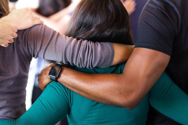 istock Group of diverse people with arms around hugging each other, showing unity and support. 2181646551
