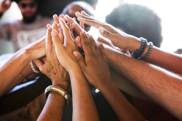 Diverse hands of various ethnicities joining upwards together in unity.