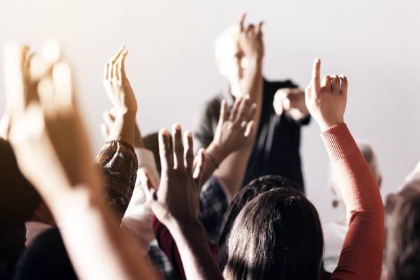 istock A diverse group of people raising hands in a classroom or seminar setting, with a focus on participation and engagement. 2181646743