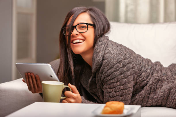 istock Happy woman using tablet and drinking coffee on sofa at home 2181646924