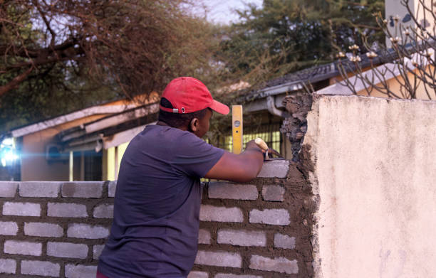 istock bricklayer african men alone, using a trowel and yellow bubble spirit level, building a wall at sunset outdoors 2181647171