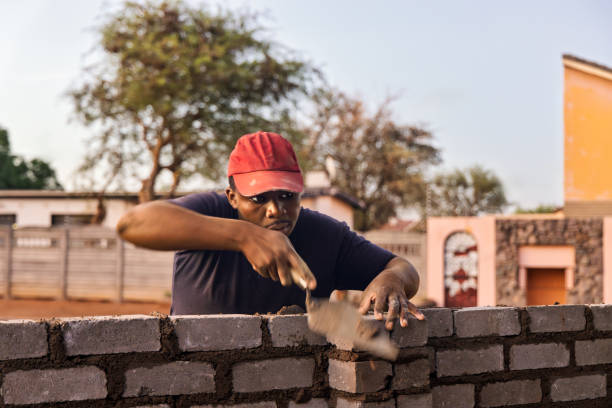 istock bricklayer african men , using a trowel and align string, building a wall at sunset outdoors 2181647505