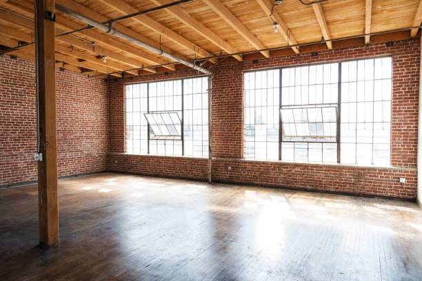 Spacious loft with large windows, exposed brick walls, and wooden beams.