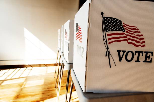 istock Voting booths with American flags in a sunlit room. 2181651792