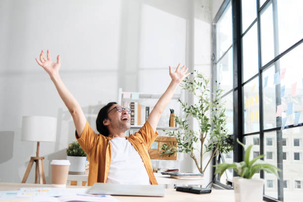Asian male worker raises his fists after finishing deadline work.