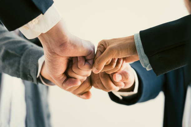 Teamwork, team building, responsibility and equal opportunities. Hand holding together bumping fists in circle as unity symbol. stock photo