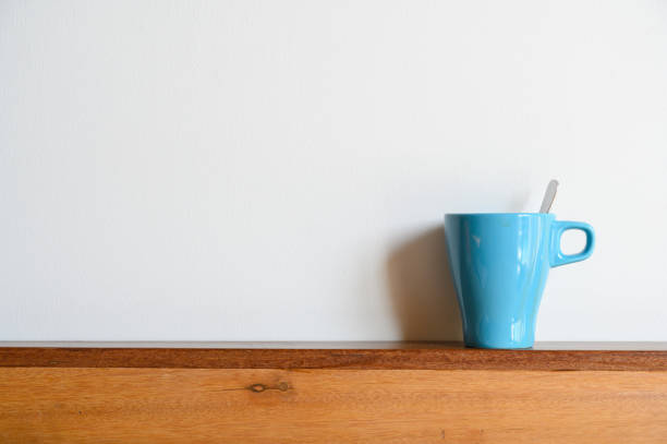 Blue coffee mug on wood table and white background with copy space. Selective focus on Coffee cup