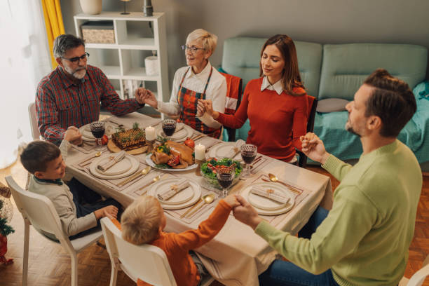 istock Family holding hands and saying grace at christmas dinner table 2181664679