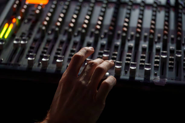 istock Hand Operating an Audio Mixing Console in a Dimly Lit Studio, Professional Sound Engineering Setup 2181666493