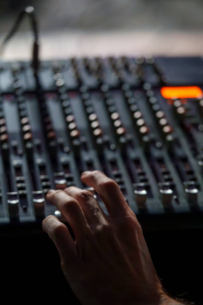 Close-Up of a Hand Operating an Audio Mixing Console in a Dimly Lit Studio, Professional Sound Engineering Setup