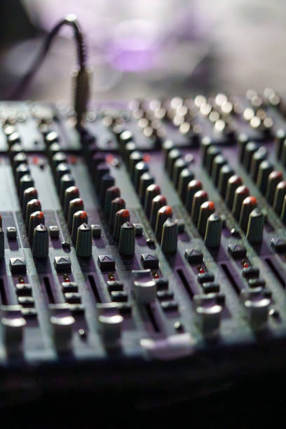 Close-up of an Audio Mixing Console with Faders and Knobs in Low Light