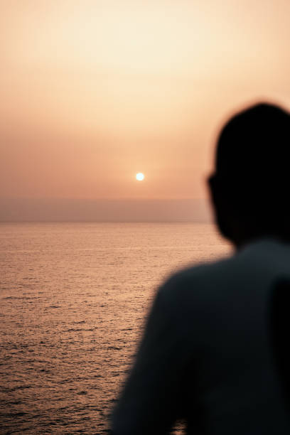 istock Defocused Silhouetted man watching the sunset over the calm ocean waters 2181667219