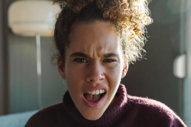 Young woman is experiencing a moment of intense shock or surprise, her mouth wide open in a scream as she reacts to something unexpected