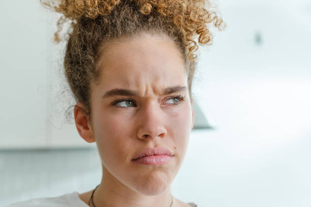 Close-up of a young woman indoors with a puzzled and doubtful expression, conveying emotions of confusion and uncertainty.