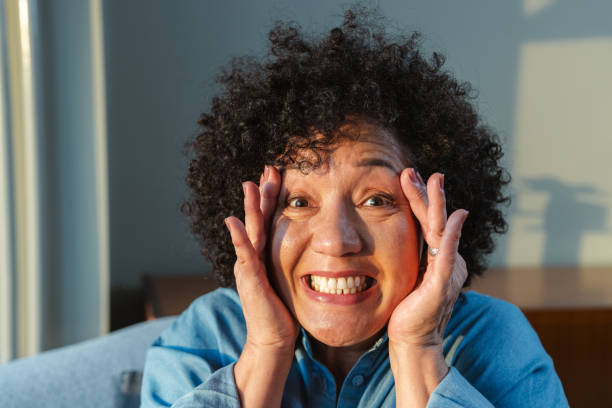 istock Surprised woman with hands on face expressing joy at home 2181671365