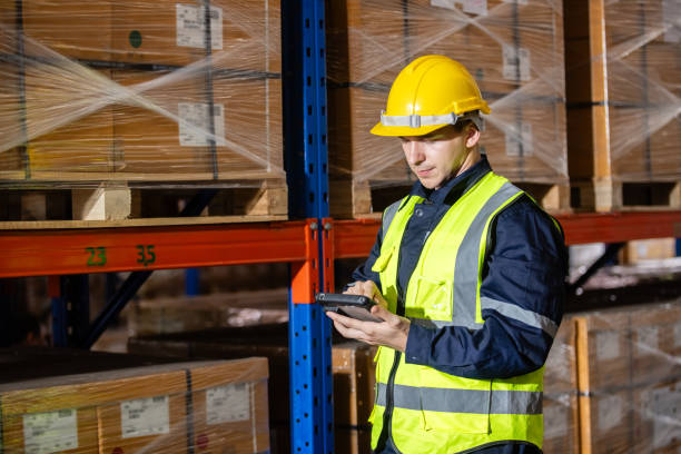 istock Male professional worker wearing safety uniform and hard hat using digital tablet inspect product on shelves in warehouse. Man worker check stock inspecting in storage logistic factory. 2181674449