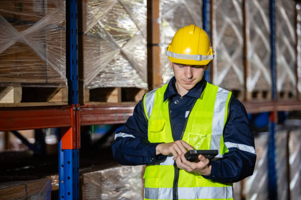 istock Male professional worker wearing safety uniform and hard hat using digital tablet inspect product on shelves in warehouse. Man worker check stock inspecting in storage logistic factory. 2181674451