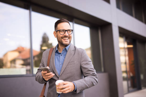 istock Well dressed handsome businessman using phone while walking in the city 2181675386