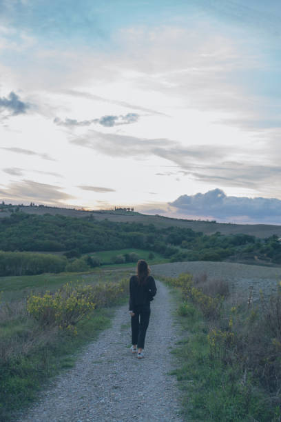 istock Young woman walks down rural road at dusk 2181675433