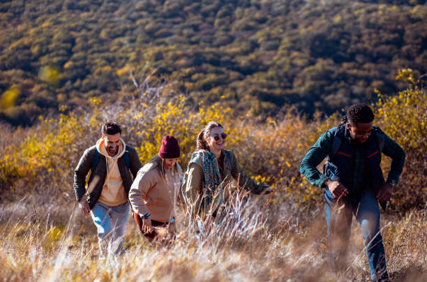 istock Smiling group of friends having fun while hiking together on hill at sunset. 2181688628